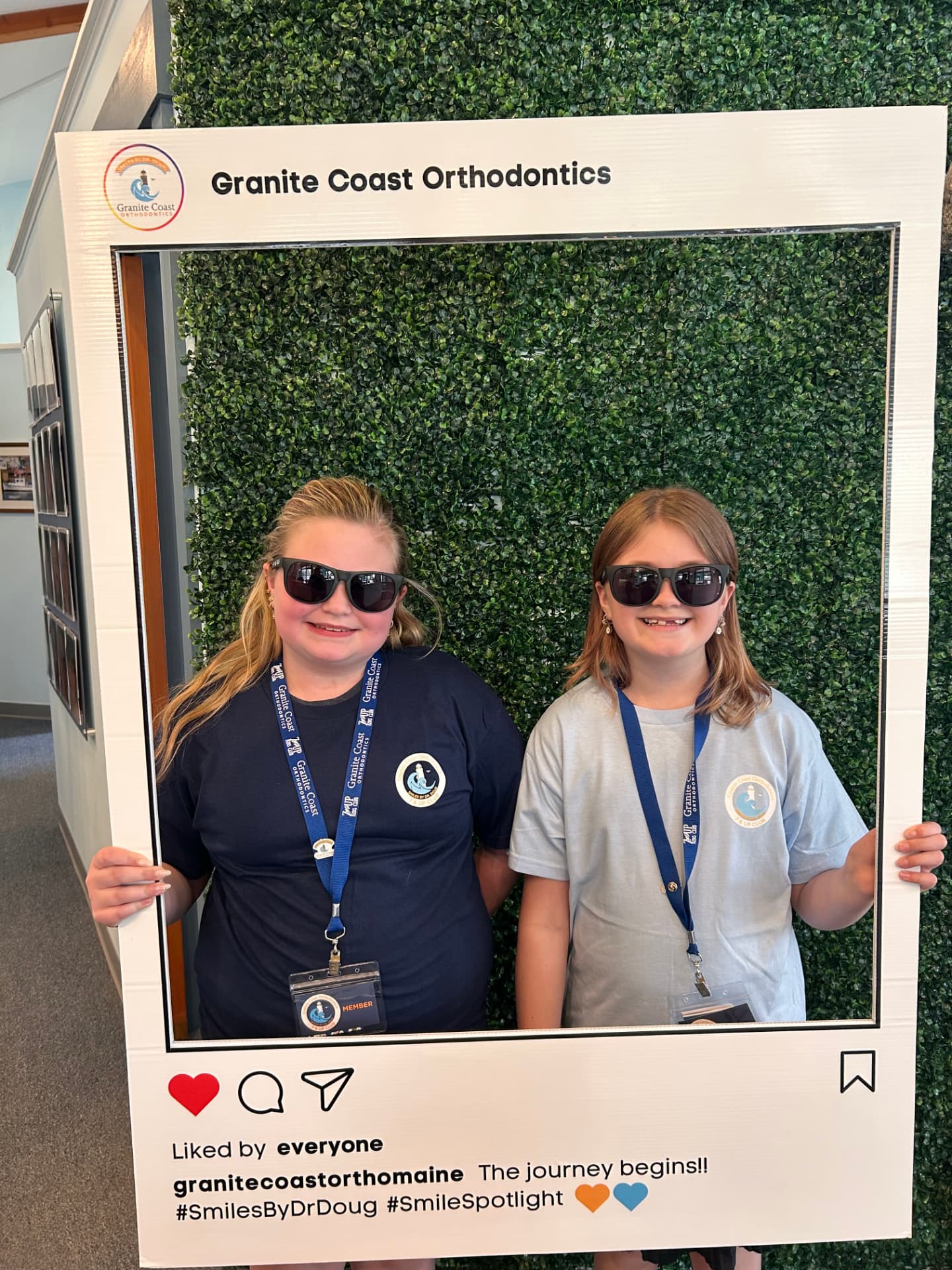 Two 7 & Up Club members holding the Granite Coast Orthodontics photo frame in the office