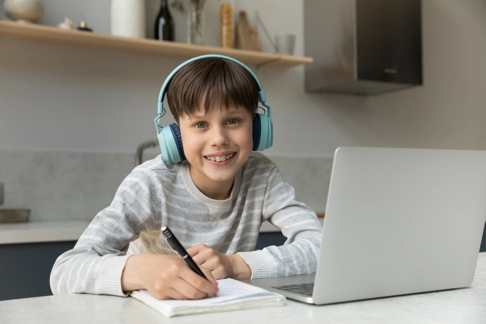 Child smiling while using a laptop